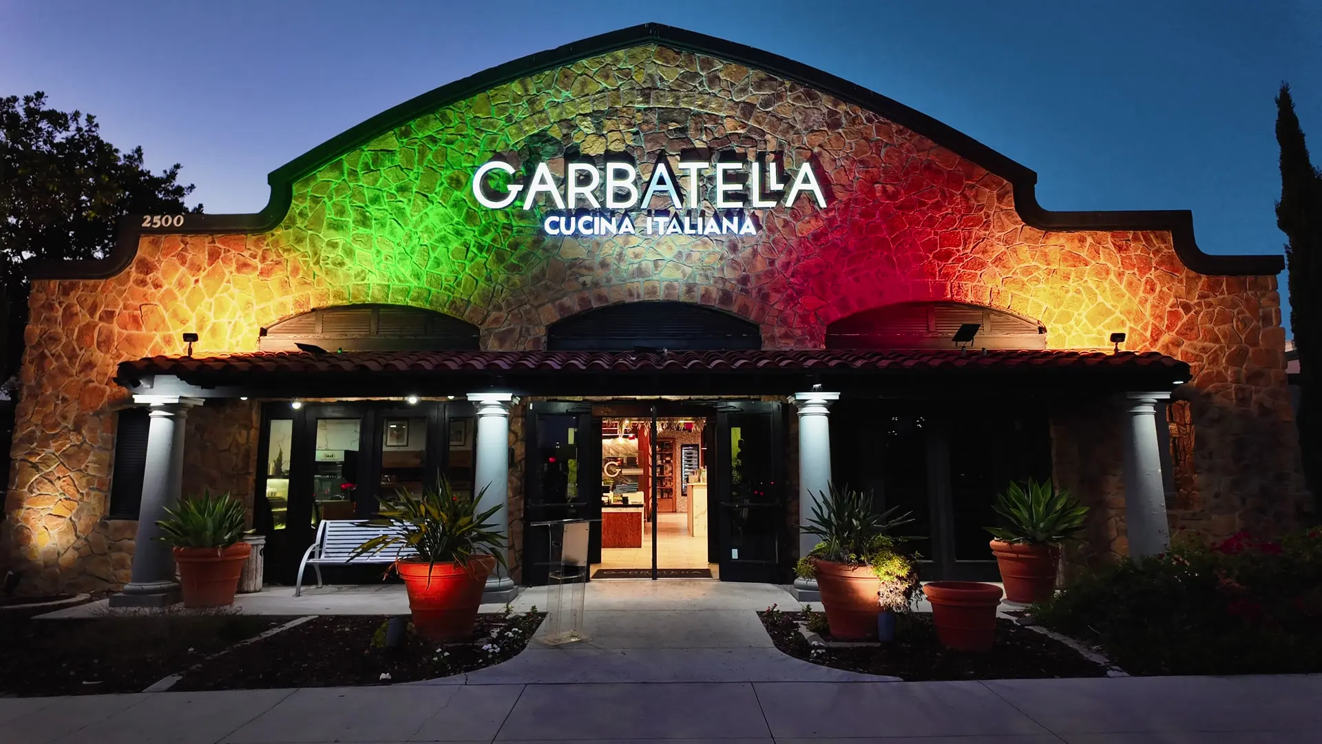 Garbatella at blue hour, the stone façade lit in the colors of the Italian flag