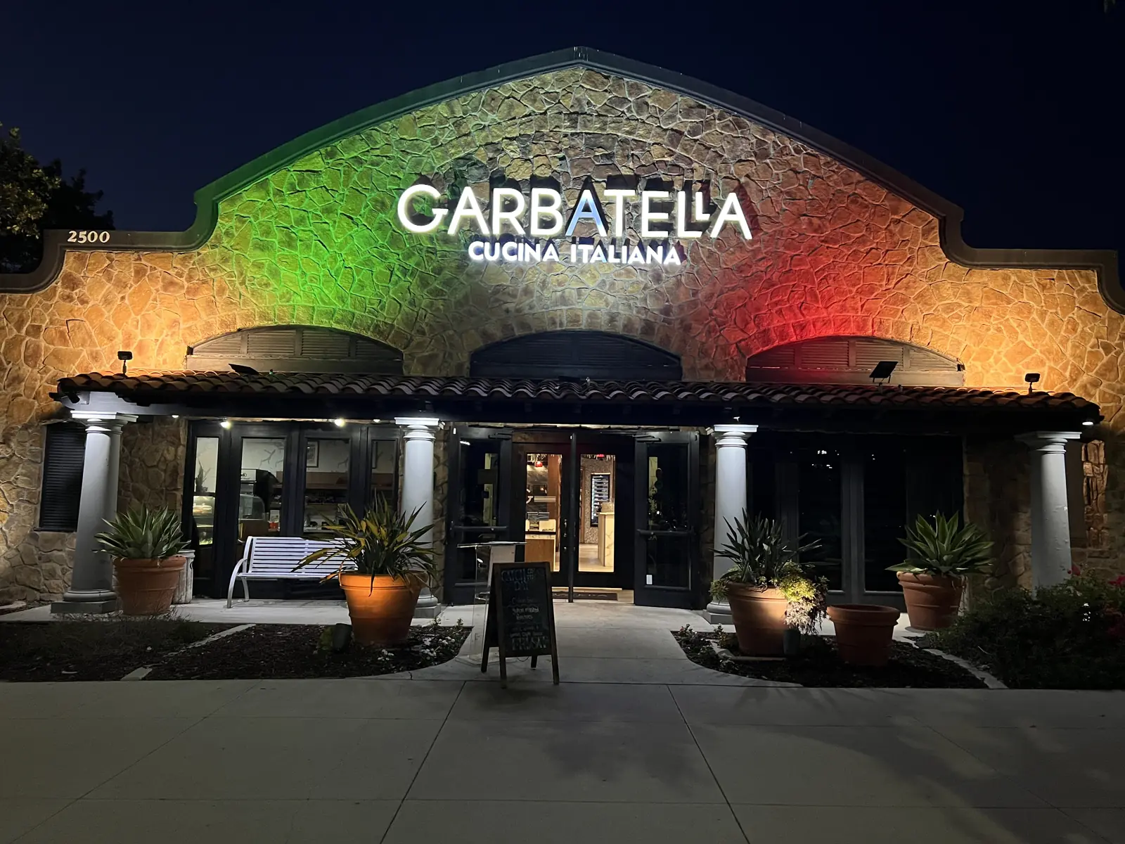 Garbatella at night, the stone façade lit in the colors of the Italian flag