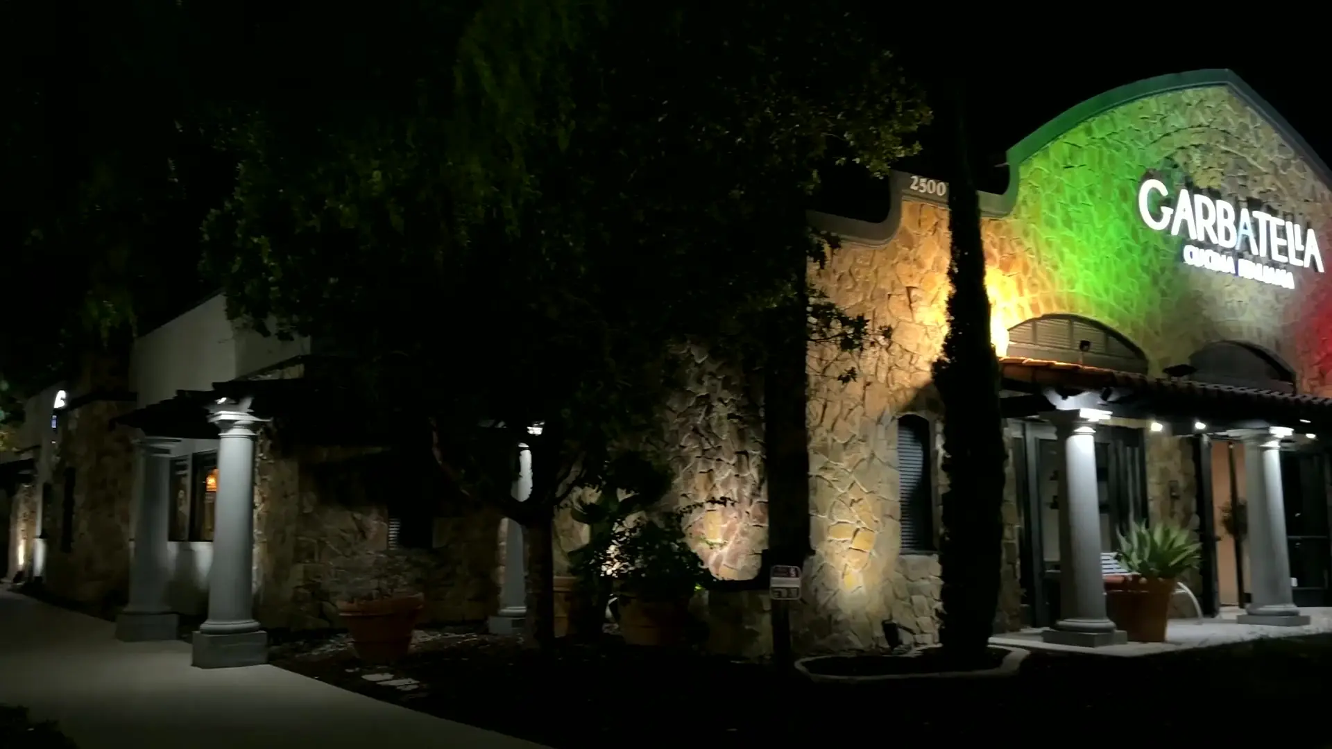Walking up to Garbatella at night, the stone façade lit green, white and red